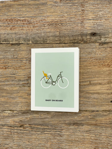 Card with bicycle and baby buggy illustration on a wooden surface