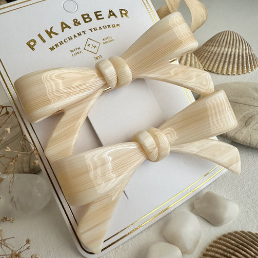 Beidge bow tie hair clip on a branded Pika and bear box with natural elements around