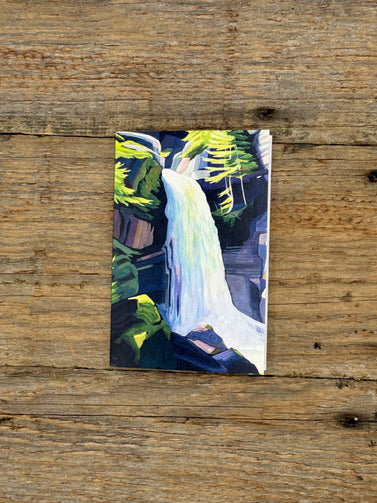 Greeting card with painting of a waterfall on a wooden surface