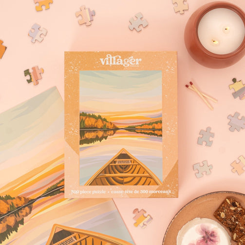 Villager puzzle box with a scenic illustration on a pink background with puzzle pieces and a candle.