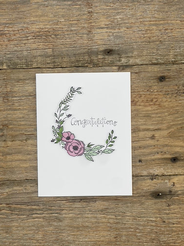 Greeting card with floral design and 'Congratulations' text on a wooden surface
