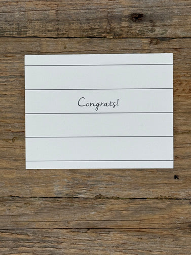 White card with 'Congrats!' on a wooden surface