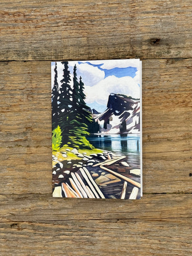 Greeting card with a mountain and lake illustration on a wooden surface