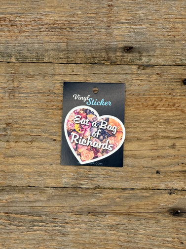 Heart-shaped vinyl sticker with floral design and text on a wooden surface