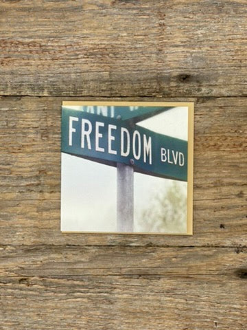 Street sign reading 'Freedom Blvd' on a wooden background