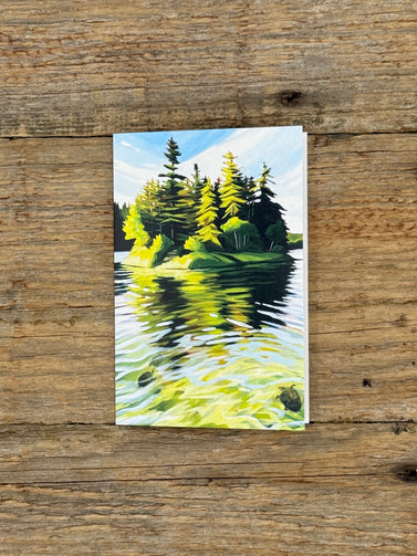 Painting of a forest reflected in water on a wooden surface