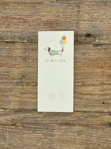 Note card with a dachshund illustration and 'Get well soon' text on a wooden surface