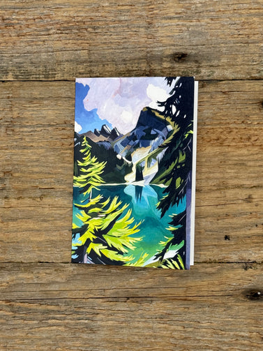 Greeting Card with a mountain and pine tree design on a wooden surface