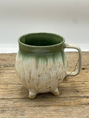 Green ceramic mug with a textured surface on a wooden surface