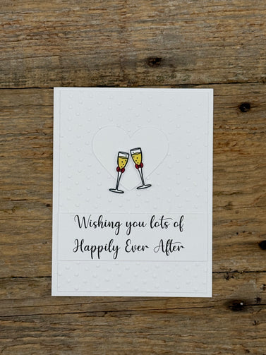 Greeting card with champagne glasses and text 'Wishing you lots of Happily Ever After' on a wooden surface