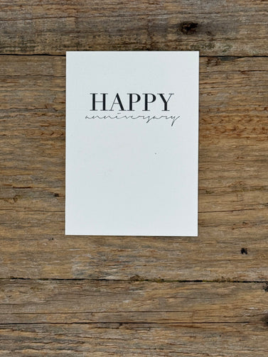 White card with 'Happy anniversary' text on a wooden surface