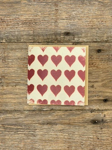Card with red heart pattern on a wooden surface