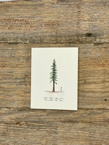 Note card with a tree illustration and text on a wooden surface