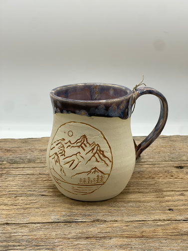 Ceramic mug with mountain design on a wooden surface