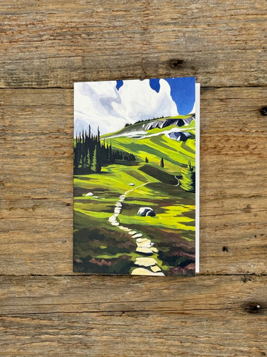 Painting of a landscape with green fields and trees on a wooden surface