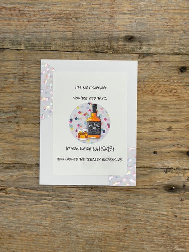 Card with a bottle illustration and humorous text on a wooden surface