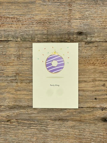 Greeting card with purple donut design on a wooden surface