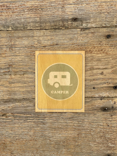 Card with camper illustration and 'Camper' text on a wooden surface