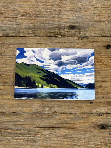 Small painting of a landscape with trees and water on a wooden surface