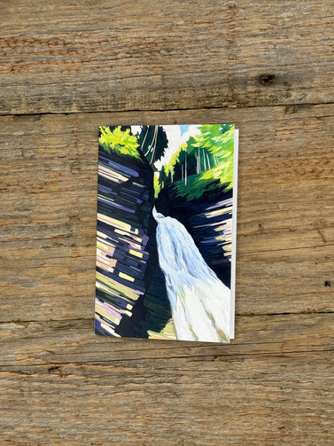 Small painting of a waterfall on a wooden surface
