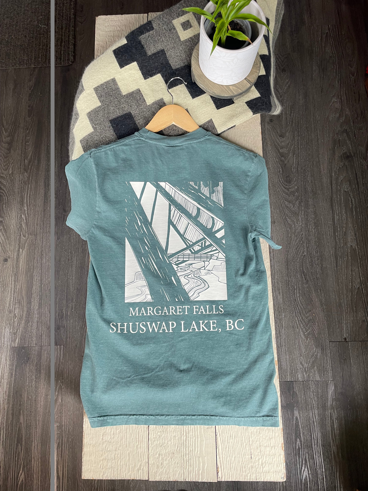 A t-shirt with a white graphic of a bridge and the text 'MARGARET FALLS SHUSWAP LAKE, BC'.