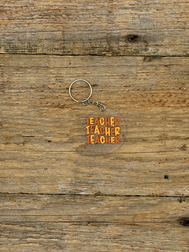 Keychain with 'TEACHER' text on a wooden surface