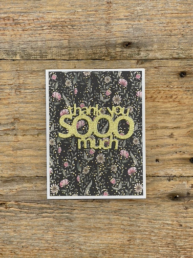 Greeting card with 'thank you SOOO much' text on a floral patterned background, placed on a wooden surface.