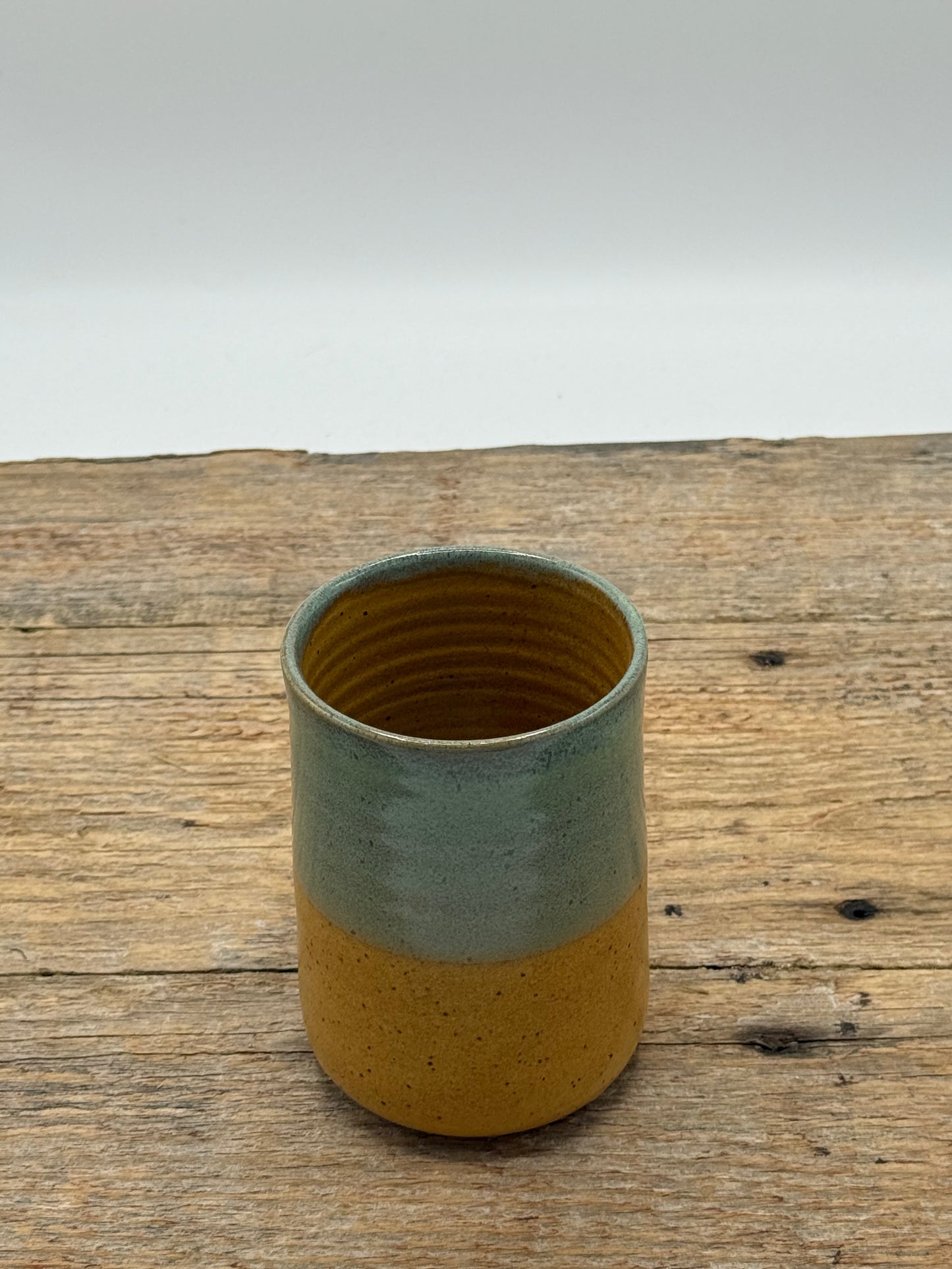 Two-toned ceramic cup on a wooden surface with a white background