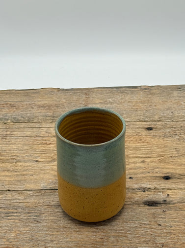 Two-toned ceramic cup on a wooden surface with a white background