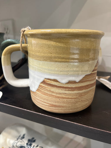 Handmade ceramic mug with striped design on a dark surface