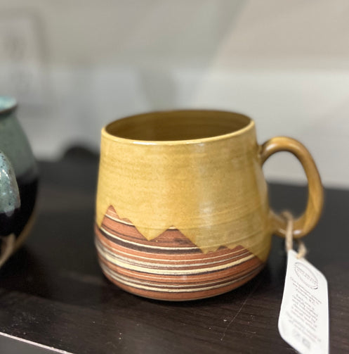 Ceramic mug with mountain design on a dark surface