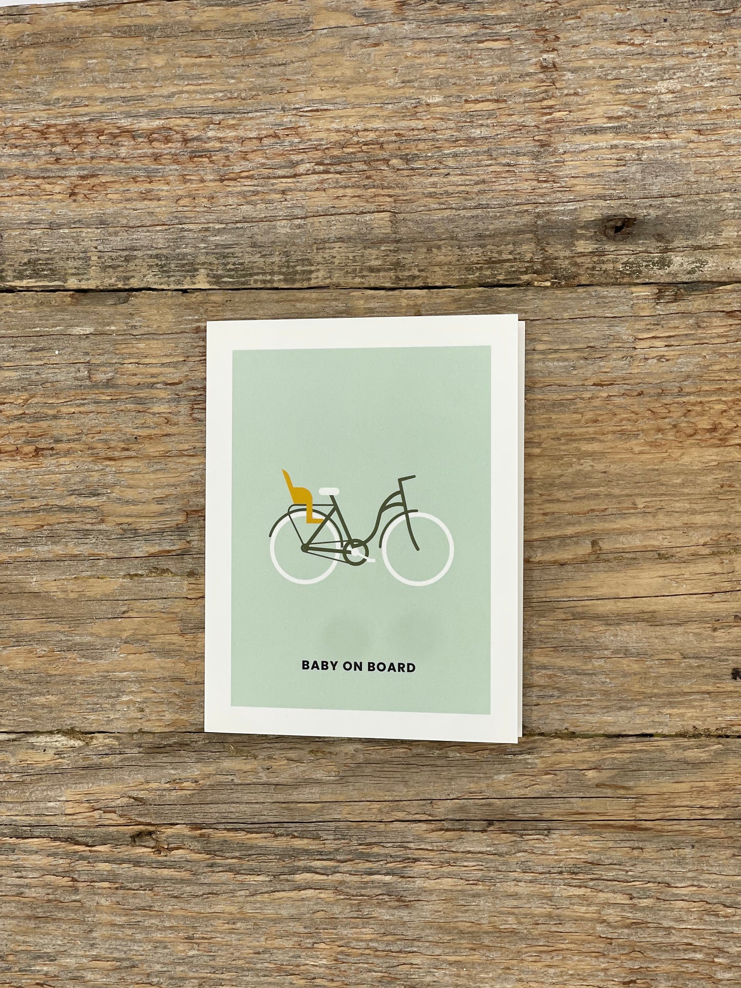 Card with bicycle and baby buggy illustration on a wooden surface