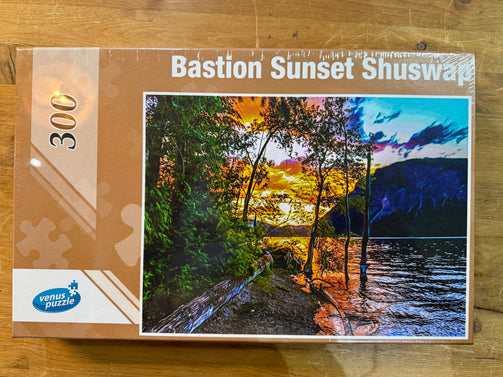 Jigsaw puzzle box titled 'Bastion Sunset Shuswap' by Venus Puzzle on a wooden surface.