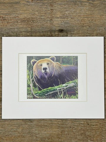 Matted print of a bear in a natural setting on a wooden surface