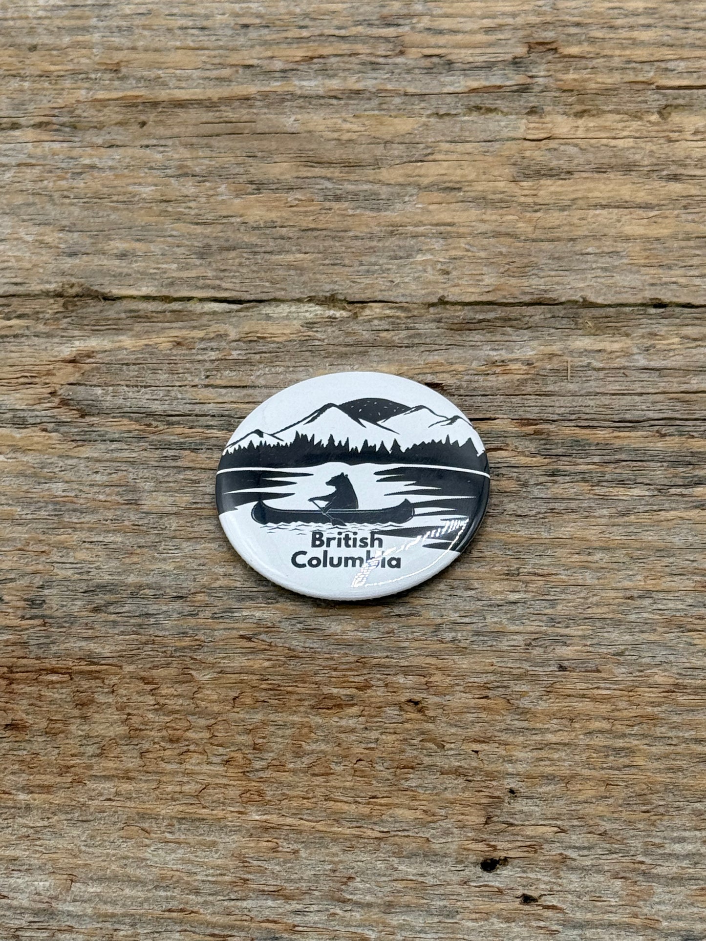 Round sticker with a canoe design and 'British Columbia' text on a wooden surface