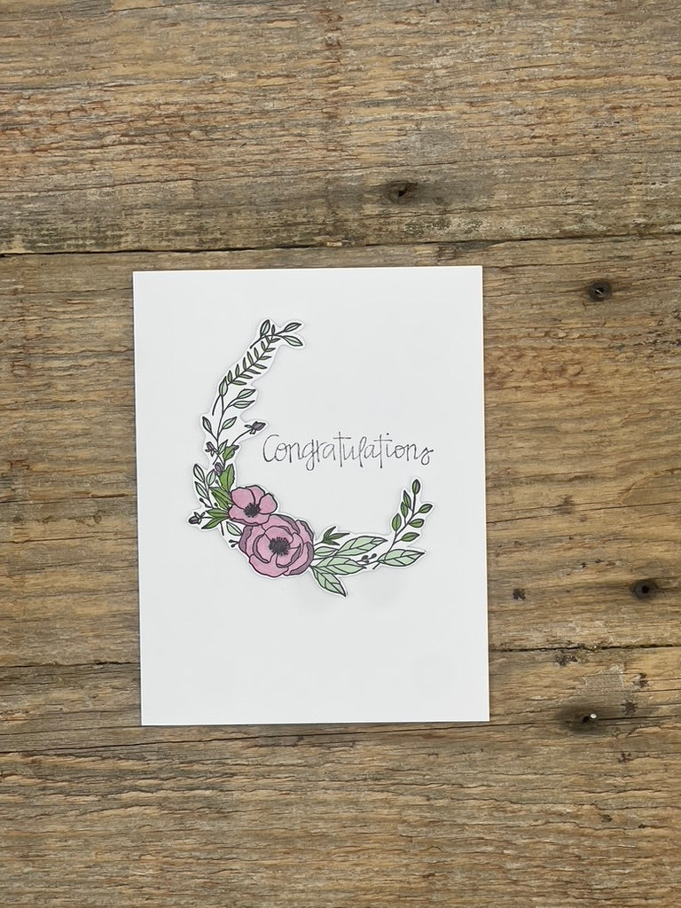 Greeting card with floral design and 'Congratulations' text on a wooden surface