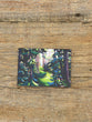 Forest scene postcard on a wooden surface