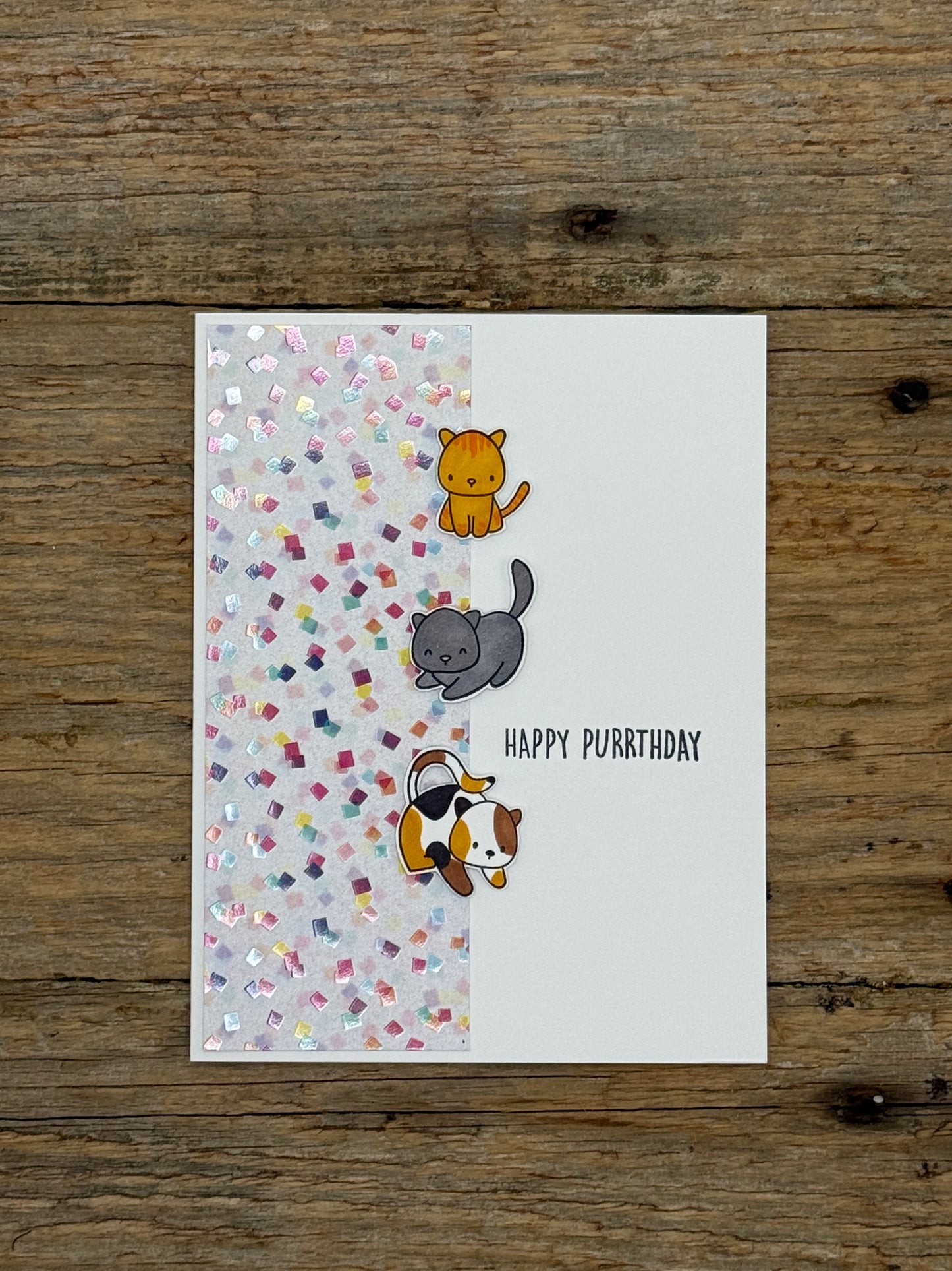 Greeting card with cartoon cats and 'Happy Purrthday' text on a wooden surface