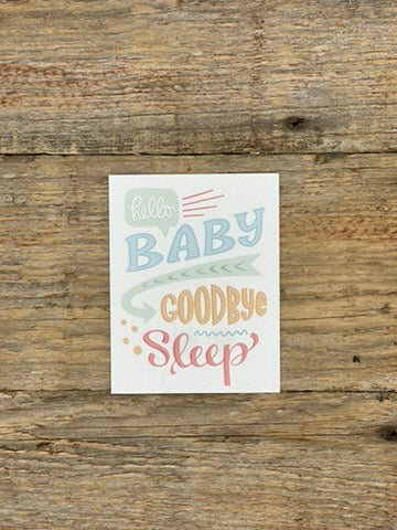 Card with 'Hello Baby, Goodbye Sleep' text on a wooden surface