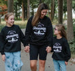 Woman and two children wearing matching black sweatshirts with 'Shuswap BC' text, standing outdoors.
