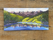 Painting of a mountain landscape with a lake on a wooden surface