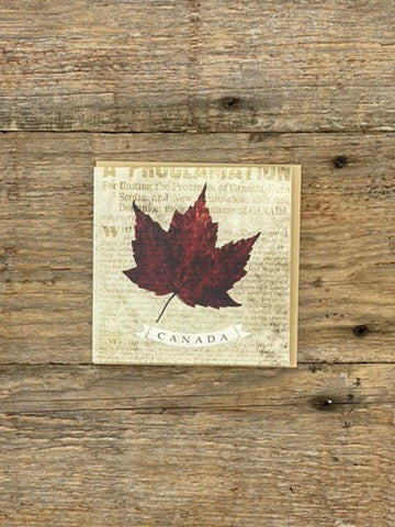 Maple leaf poster with 'Canada' text on a wooden background
