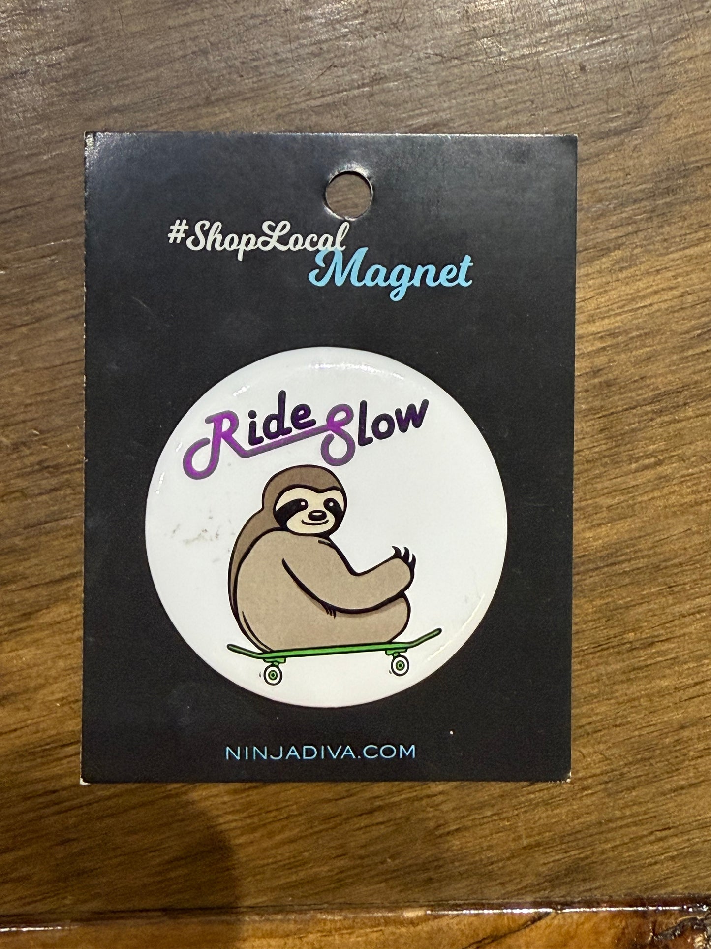 Ride slow sloth magnet on a black backing card with branding text.