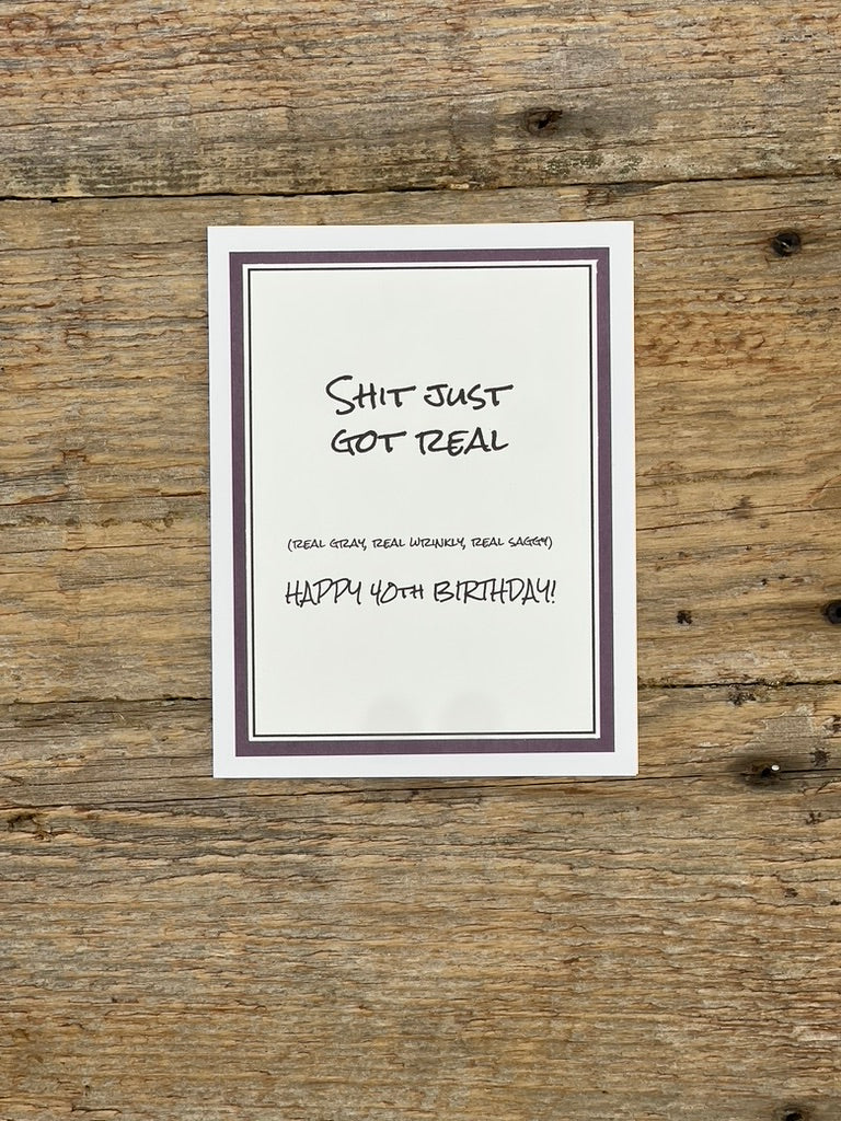 Framed birthday card with humorous text on a wooden surface