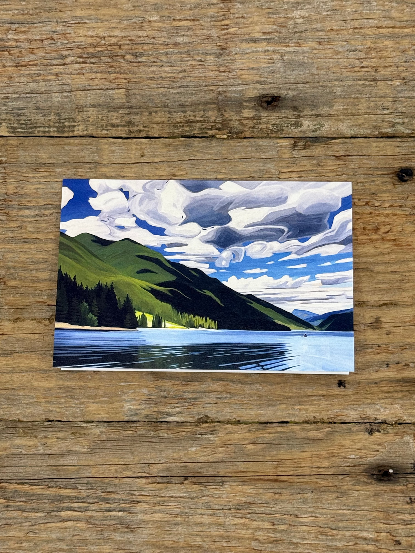 Small painting of a landscape with trees and water on a wooden surface