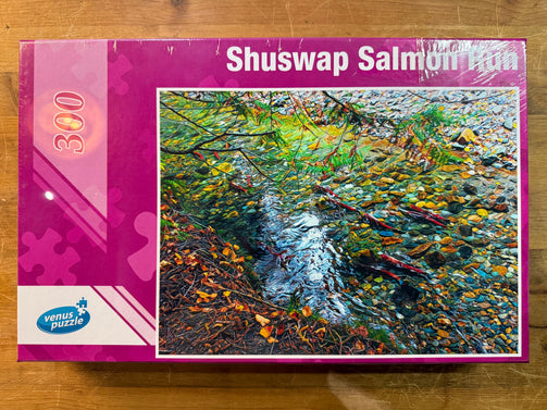 Jigsaw puzzle box featuring a colorful depiction of a salmon run in a stream, with 'Shuswap Salmon Run' text and Venus Puzzle logo.