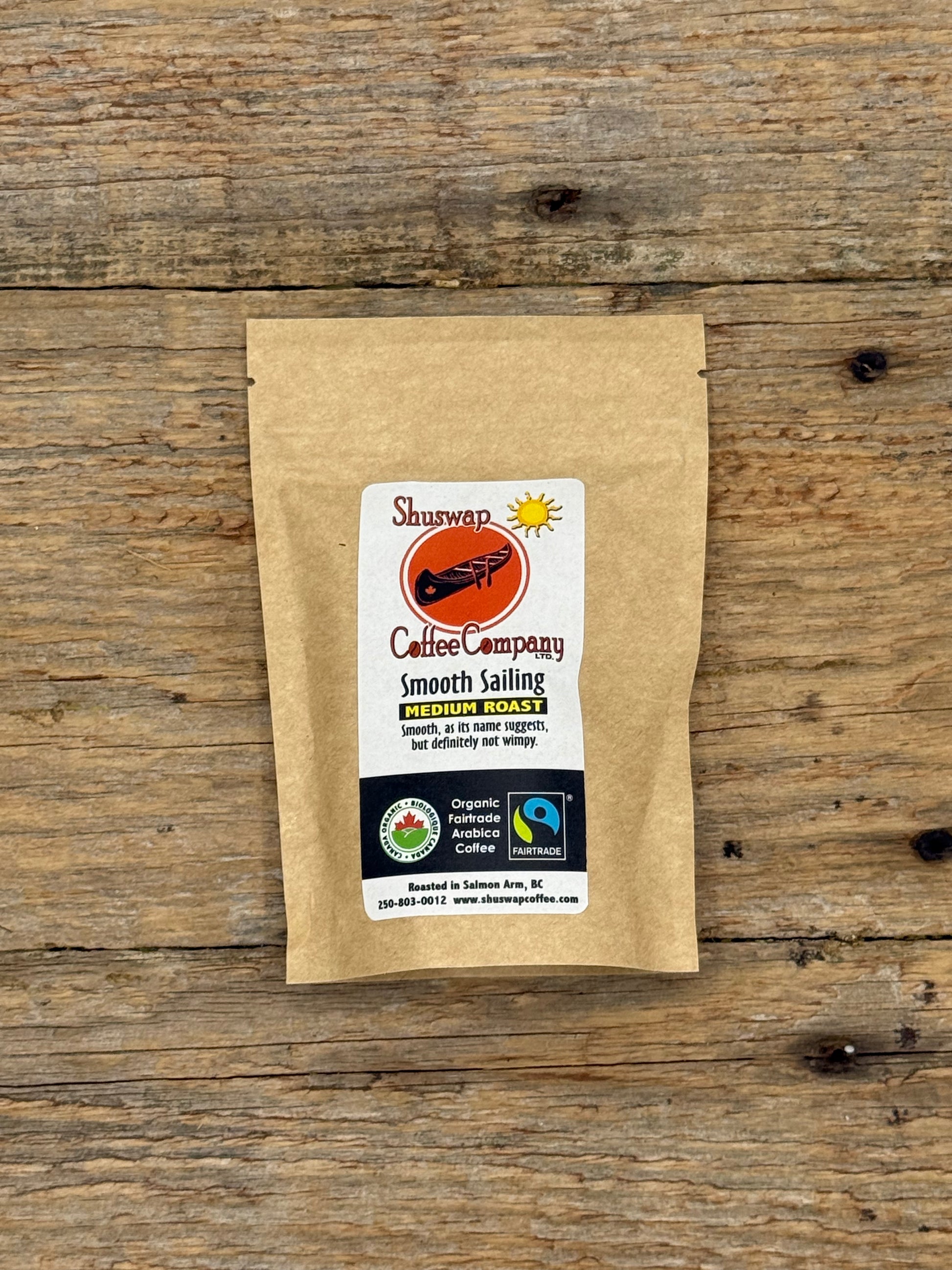 Kraft paper coffee package with a label on a wooden surface. Smooth Sailing Coffee by Shuswap Coffee Company