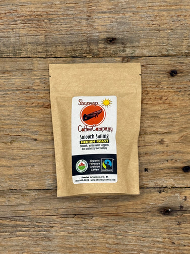 Kraft paper coffee package with a label on a wooden surface. Smooth Sailing Coffee by Shuswap Coffee Company