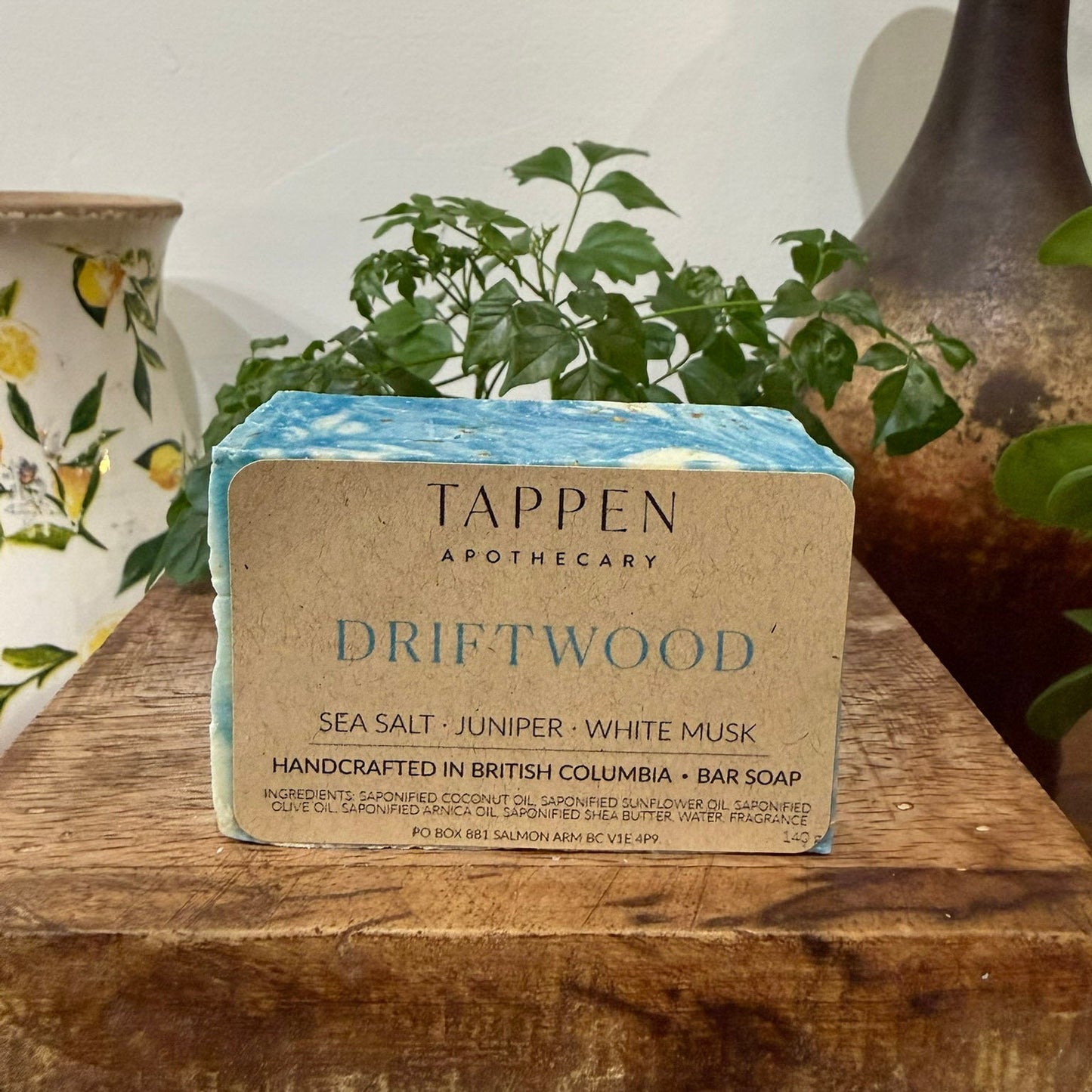 Tappen Apothecary Driftwood soap bar on a wooden surface with plants and decorative items in the background.