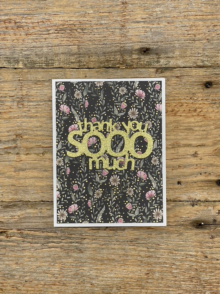 Greeting card with 'thank you SOOO much' text on a floral patterned background, placed on a wooden surface.